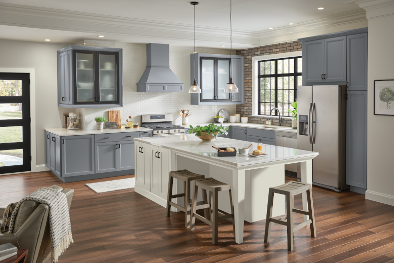A kitchen with gray-blue cabinets, a white island, and hardwood floors.