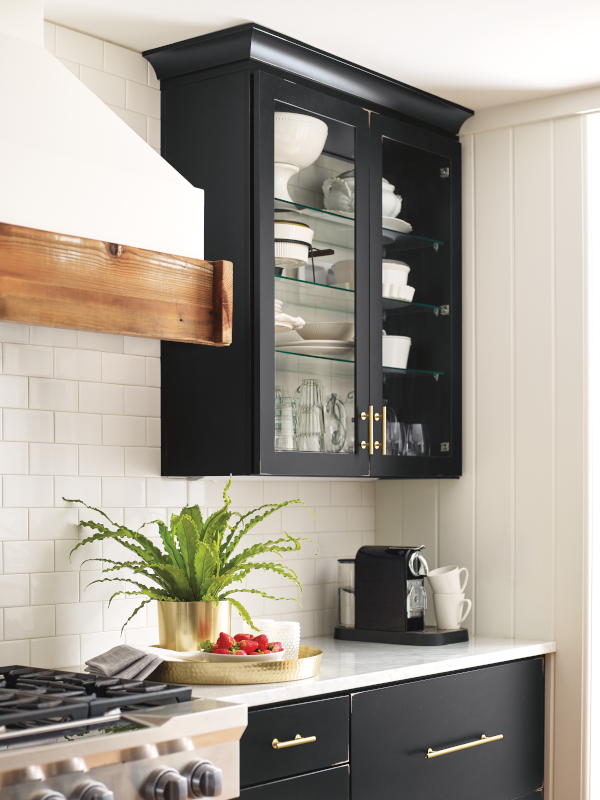 Black upper cabinets with glass fronts that display the dishware within.