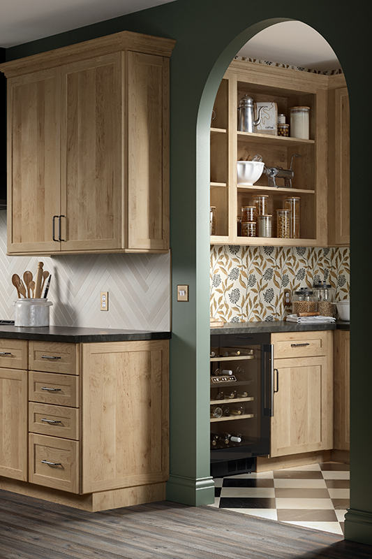A kitchen with wood toned cabinets that wrap around a corner and through an archway.