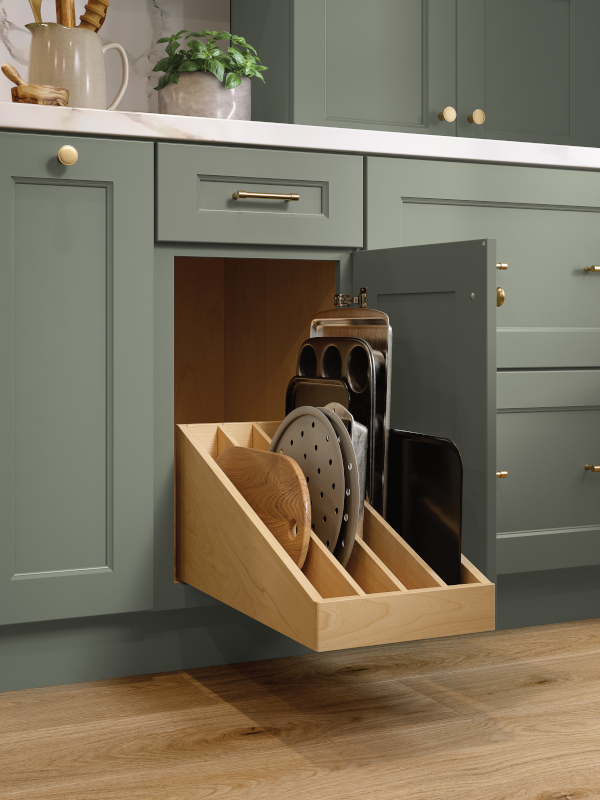 A close-up of a concealed kitchen tray divider pull out from green kitchen cabinets.