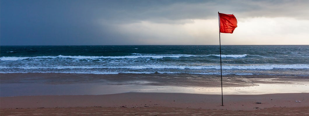 Storm warning flags on beach. Hurricane preparation guide.