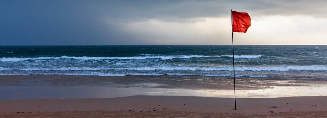 Storm warning flags on beach. Hurricane preparation guide.