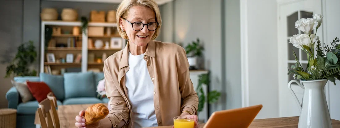 A mature woman has a croissant for breakfast. Condo Liability Insurance.