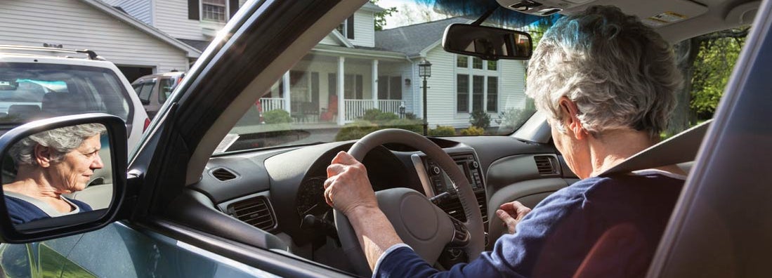 Woman in car pulling out of driveway from home. Find Maine Umbrella Insurance.