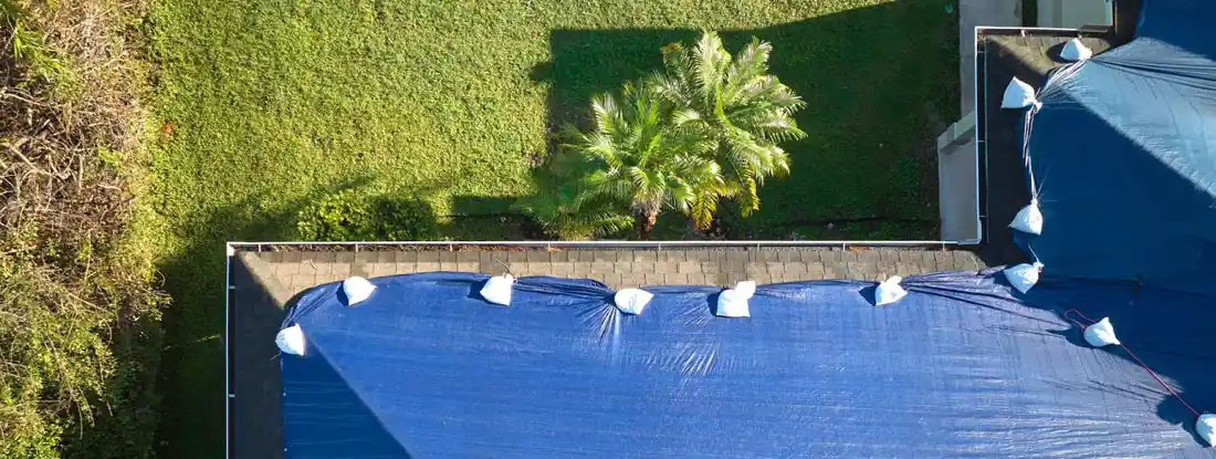 Leaking house roof covered with protective tarp sheets. Does Homeowners Insurance Cover Roof Leaks?