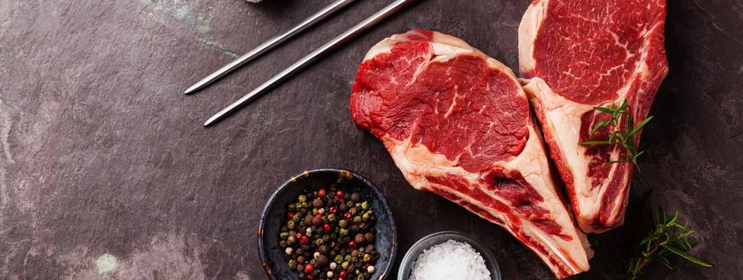 Ribeye Steak with rosemary, pepper and salt on stone slate background. Find Butcher Shop Insurance.