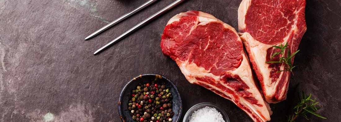 Ribeye Steak with rosemary, pepper and salt on stone slate background. Find Butcher Shop Insurance.