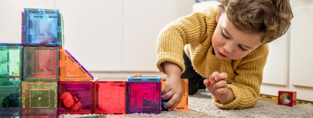 Child playing with magnetic bright multicolored tiles. Find daycare insurance.