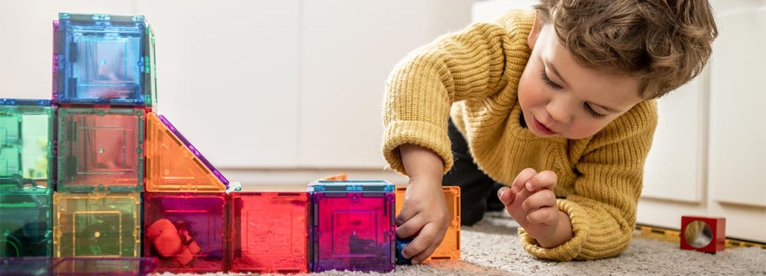 Child playing with magnetic bright multicolored tiles. Find daycare insurance.