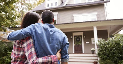 Rear View Of Loving Couple Looking At House. Top 12 Things You Wish You Knew Before Buying Your First House. 