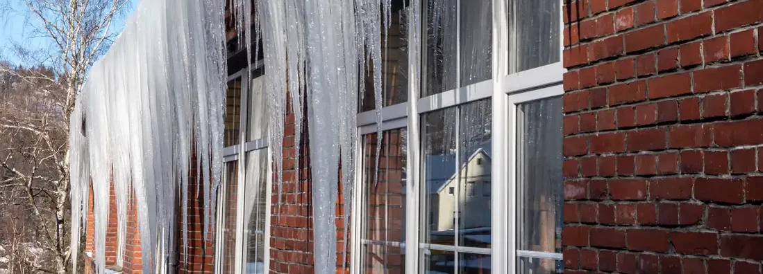 Huge icicles hang from the roof. How to Prevent Ice Dams and Who Pays for the Damage They Cause in Massachusetts.