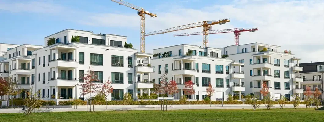 Brand new luxury townhouses with three cranes of a construction area behind the buildings. Find Condo Construction Insurance.