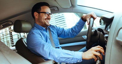 Handsome man driving car. Find Car Insurance Discounts.