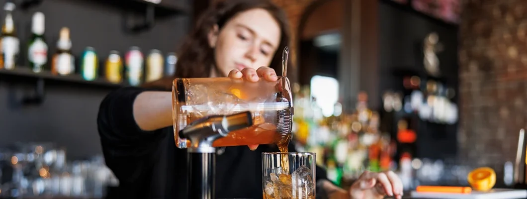 Female bartender making cocktail. Find Liquor Liability Insurance.