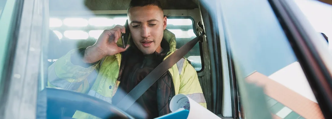 Worker is sitting in his van, looking through paperwork. Kentucky Commercial Vehicle Insurance.