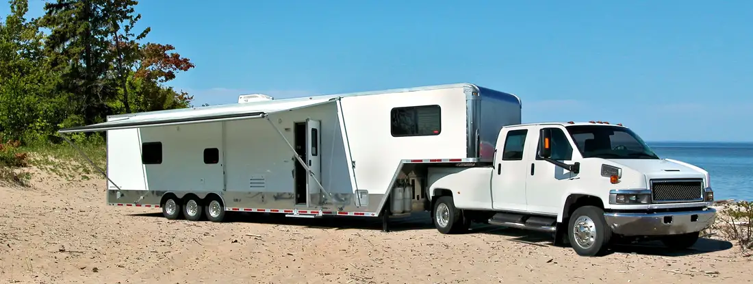 White toy hauler travel trailer camping on the sandy shore of Lake Superior. Find Toy Hauler Insurance.