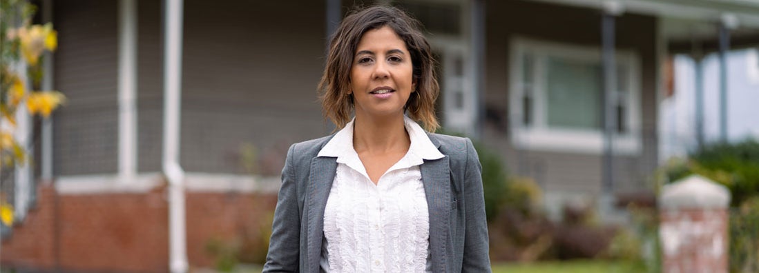 Female landlord in front of a house. Find Kansas landlord insurance.