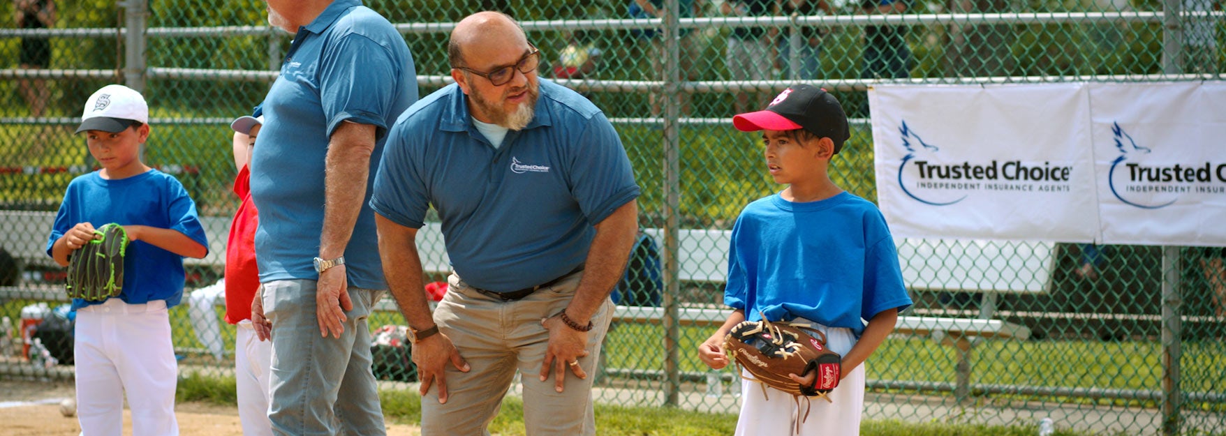 Young boy baseball player with his coach getting instructions. Get homeowner's insurance.