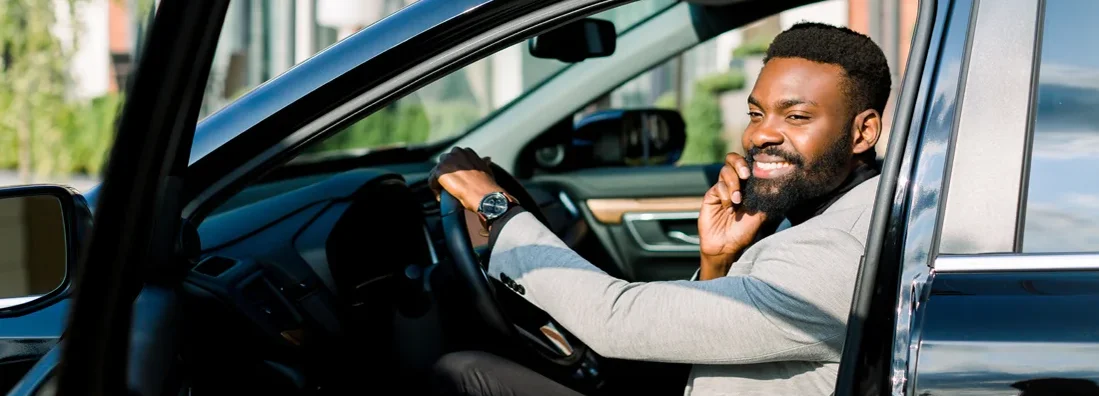Man sitting in car talking by the phone. How to Find the Best Car Insurance in Brookline, NH.