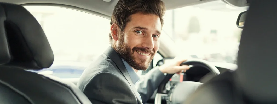 Man in his car driving and facing camera. Find New York Commercial Vehicle Insurance.
