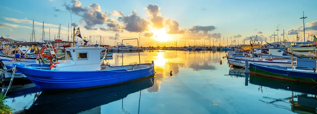 A sunset over lake with a port in the background. Find Ohio Boat Insurance.