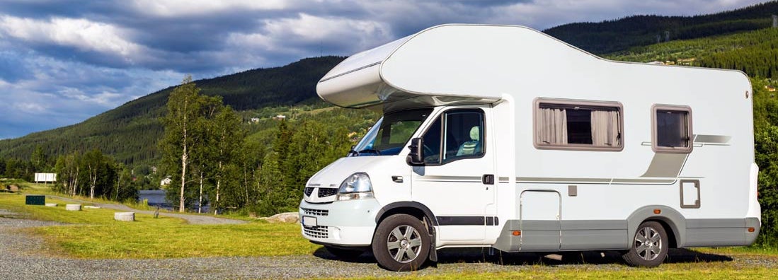 Modern white RV at camping site in beautiful New Hampshire. Find New Hampshire RV Insurance.