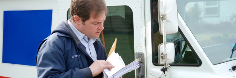 Mail carrier sorting mail near delivery truck