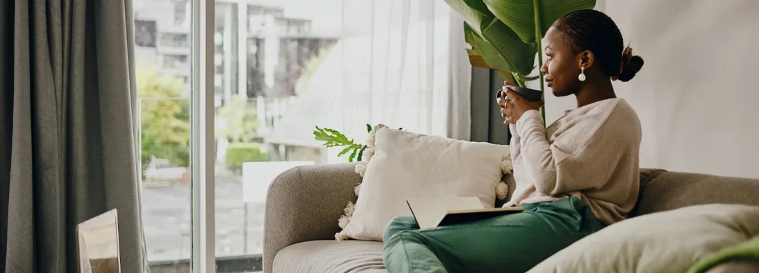 Young woman having coffee and relaxing in apartment. What Does Renters Insurance Cover?