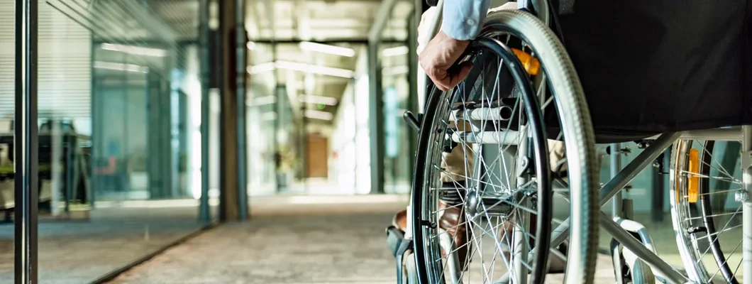 Paralyzed man in a wheelchair on the move in the disabled office building. Short and Long-Term Disability Insurance Defined.
