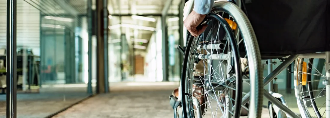 Paralyzed man in a wheelchair on the move in the disabled office building. Short and Long-Term Disability Insurance Defined.