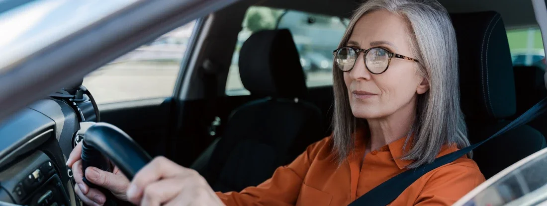 Senior woman driving new car. How to Buy a Car If You're Upside Down on Your Loan.