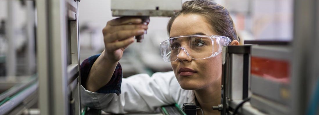 Female engineer examining machine part on a production line. Find Manufacturer's Insurance.