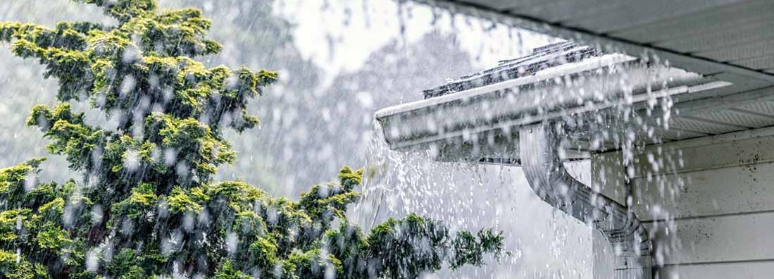 Downpour rain water overflowing over the overhanging eaves of gutter system. Gutter Floods.