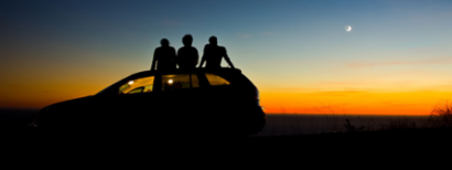 Friends sitting on a new car watching the sunset.