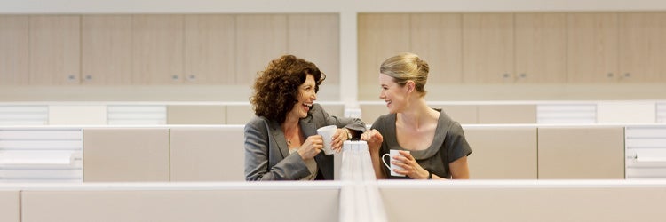 Businesswomen with coffee gossiping in office cubicles