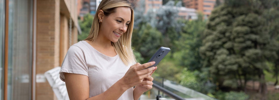 Woman using her phone from the balcony of her apartment. Find Wyoming renters insurance.