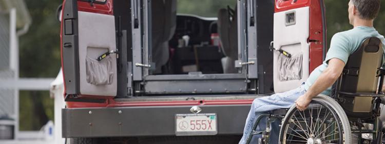 man in wheelchair looking at the chair lift in a van