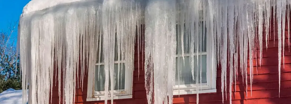 Long, big and dangerous icicles on a brick house roof. Beware of ice dams on your Illinois home.
