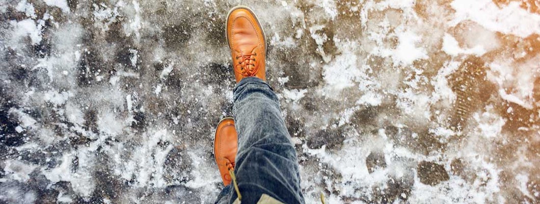 Feet of a man walking along the icy pavement. Who’s Responsible for an Icy Sidewalk Slip and Fall?