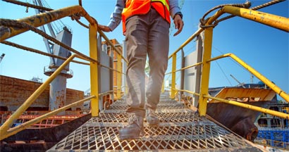 Engineer walking on the steel bridge cross over at workplace. Find Best Companies Workers' Compensation.