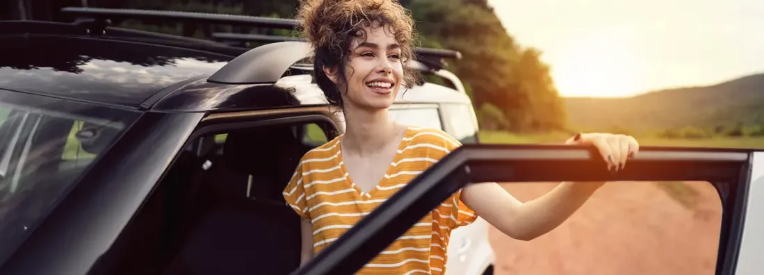 Woman standing by car and looking away. Find Huntsville, Alabama car insurance.