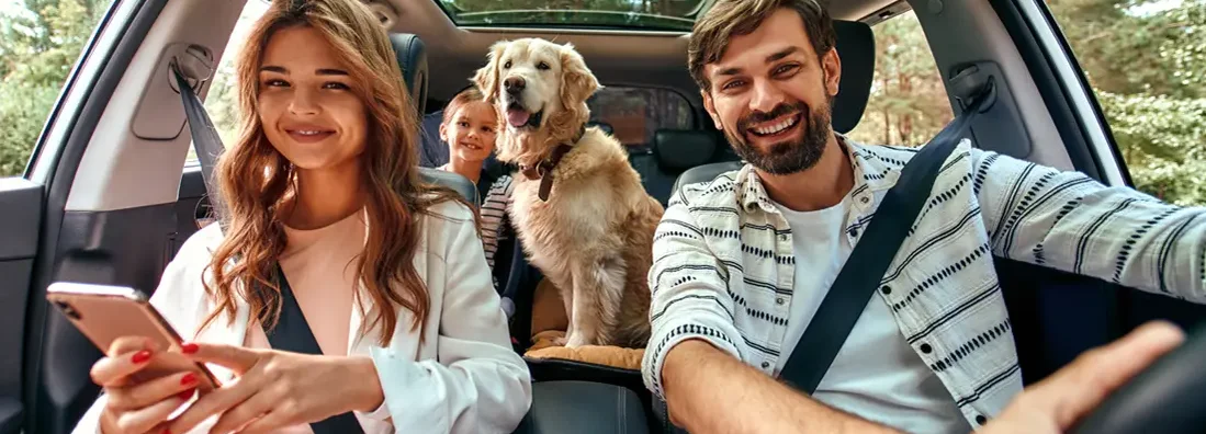 Family with dog in the car. The Dangers of Driving with Pets and How to Keep Them Safe. 