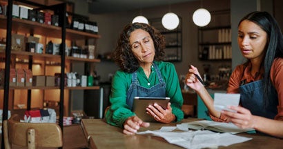 Manager and an employee going over receipts at a table. How to Get a Mortgage As a Self-Employed Business Owner.