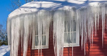 Long, big and dangerous icicles on a brick house roof. Beware of ice dams on your Illinois home.