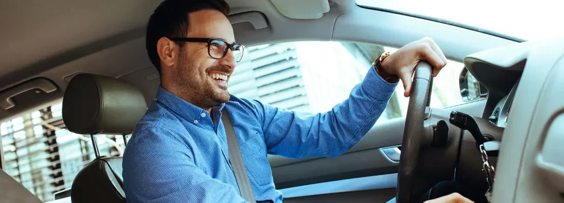 Handsome man driving car. Find Car Insurance Discounts.