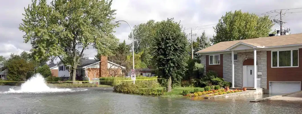 Residential street and house flood by water after an underground water pipe broke. Find Missouri Flood Insurance.