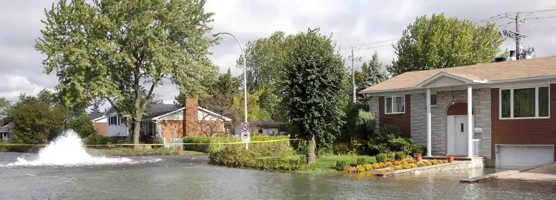 Residential street and house flood by water after an underground water pipe broke. Find Missouri Flood Insurance.