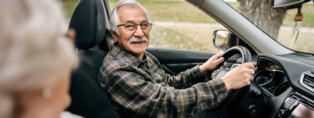 Senior couple on a road trip in a car together. Find auto insurance for seniors.