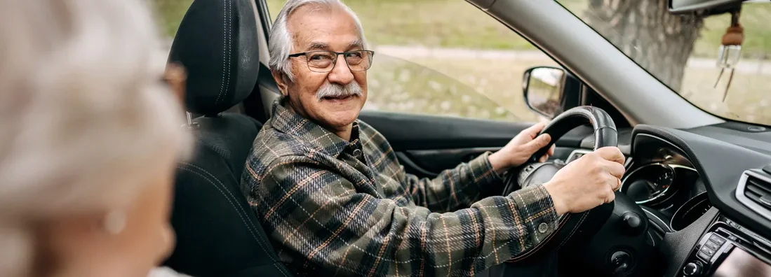 Senior couple on a road trip in a car together. Find auto insurance for seniors.