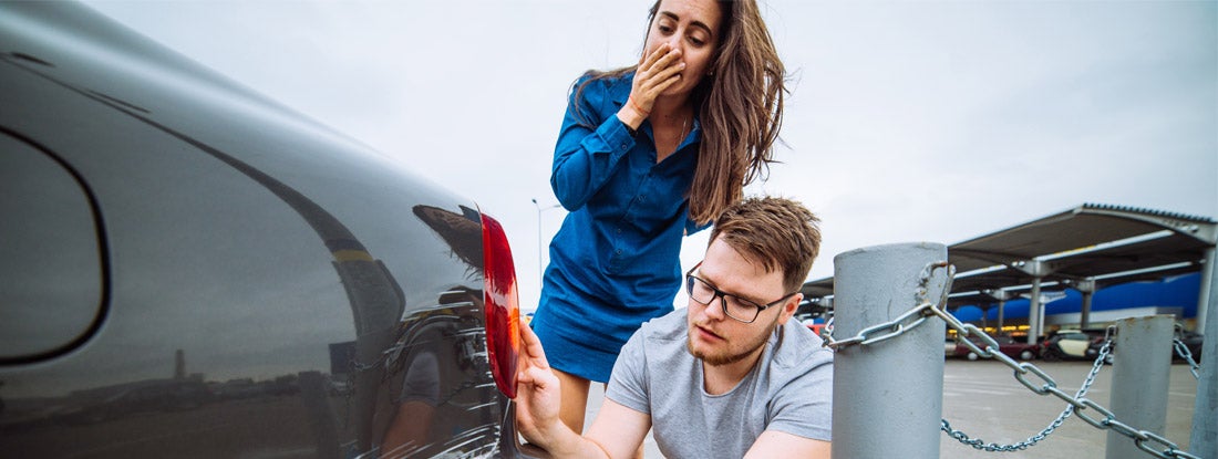 couple examine a dent on their car